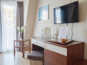 a room with a desk with a television on the wall at Holiday Beach Budapest Wellness Hotel with Sauna Park in Budapest