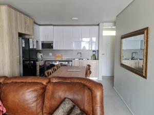 a living room with a leather couch and a kitchen at Bellamare in Gqeberha