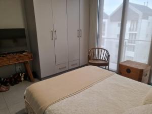 a bedroom with a bed and a tv and a chair at Bellamare in Gqeberha