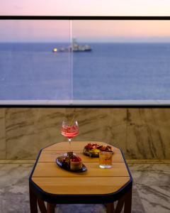 a table with a glass of wine and food on it at The Icon Limassol in Limassol