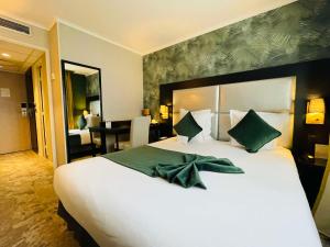 een slaapkamer met een groot wit bed met groene kussens bij Best Western Allegro Nation in Parijs