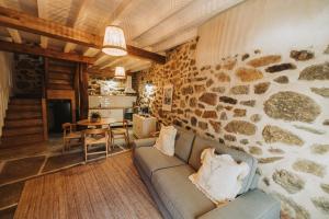 a living room with a couch and a stone wall at La casa del Mayoral in Tremedal +48 photos