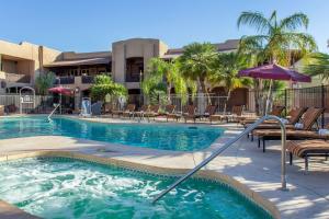 a large swimming pool with chairs and an umbrella at La Posada Lodge & Casitas, an Ascend Collection Hotel in Tucson
