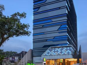 棉兰ibis Styles Medan Pattimura的一座玻璃幕墙的高楼