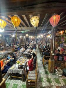 a group of people sitting at tables in a restaurant at Mai Chau Tropical Homestay in Hòa Bình +67 photos