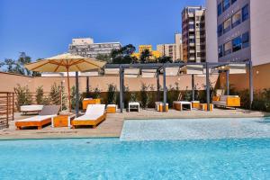 a pool with chairs and an umbrella next to a building at Radisson RED Campinas in Campinas