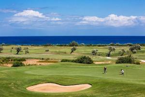 two golfers on a green with the ocean in the background at Masseria Comara in Monopoli