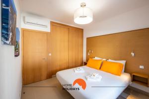 a bedroom with a large white bed with orange pillows at #251 Coronel Águas by Home Holidays in Albufeira +43 photos