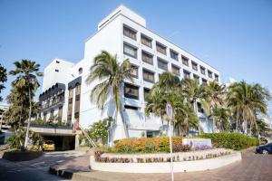 a white building with palm trees in front of it at Hotel Faranda Express Puerta Del Sol Barranquilla, A Member of Radisson Individuals in Barranquilla