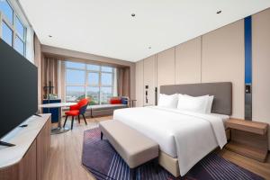 Un dormitorio con una gran cama blanca y un escritorio. en Holiday Inn Express Lvliang Xing County, en Xing