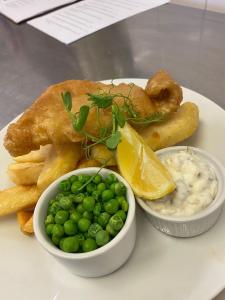 a plate of food with fish and chips and peas at The Hind Hotel in Wellingborough
