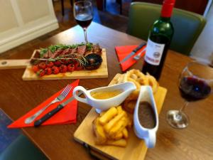 a table with two plates of food and a bottle of wine at The Hind Hotel in Wellingborough