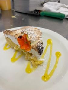 a white plate with a piece of cake with yellow sauce at The Hind Hotel in Wellingborough