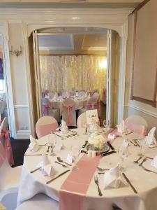 a room with a table with pink chairs and a mirror at The Hind Hotel in Wellingborough
