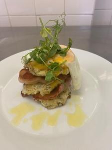 a white plate with a breakfast sandwich with eggs and greens at The Hind Hotel in Wellingborough