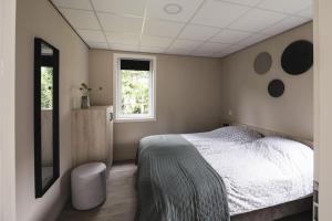 a bedroom with a bed and a window at Tiny House 'Veluwehuisje' in Voorthuizen +5 photos