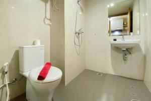 ブカシにあるHomey and Well Furnished Studio Gateway Park LRT City Jatibening Apartment By Travelioのトイレに赤いタオルが敷かれた白いバスルーム +5枚の写真