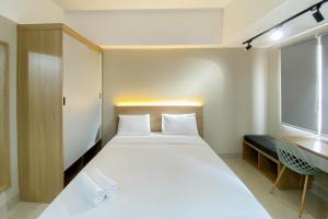 ブカシにあるHomey and Well Furnished Studio Gateway Park LRT City Jatibening Apartment By Travelioの白いベッドと窓のある寝室