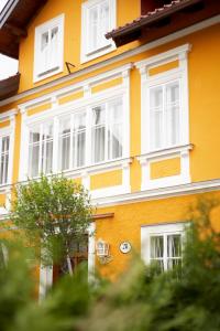 a yellow and white building with white windows at Villa Ceconi by Das Grüne Hotel zur Post - 100% BIO in Salzburg +26 photos