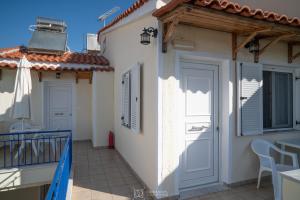 a white house with a balcony and a door at Elli Studios & Apartments in Marathokampos
