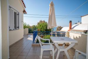 a white table and chairs on a balcony with an umbrella at Elli Studios & Apartments in Marathokampos