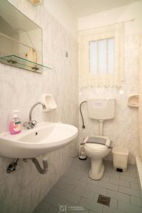 a white bathroom with a sink and a toilet at Elli Studios & Apartments in Marathokampos