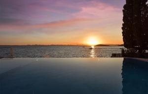 a sunset over a body of water with a swimming pool at Awesome Home In Zdrelac in Ždrelac