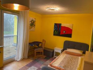 1 dormitorio con paredes amarillas, 1 cama y ventana en Ferienwohnung Ingrid Rautenberg, en Krautheim