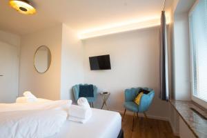 pokój hotelowy z 2 krzesłami, łóżkiem i telewizorem w obiekcie Panorama Apartments - Steinbock Lodges w mieście Zell am See