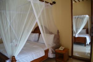 a bedroom with a bed with white curtains and a mirror at Sea View Beach Hotel in Zanzibar City +29 photos