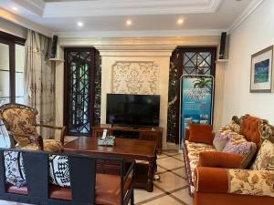 a living room with a tv and a table at Sanya beach sweet house in Luoyushangcun