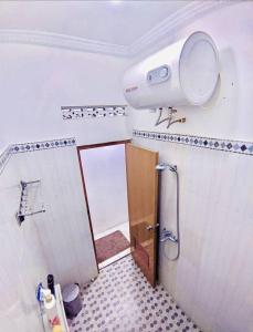 a bathroom with a shower and a light on the wall at Kamiliya Homestay in Ngabean