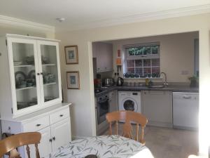 eine Küche mit weißen Schränken und einem Tisch und Stühlen in der Unterkunft Coach House Wroxham Holiday Cottage in Wroxham