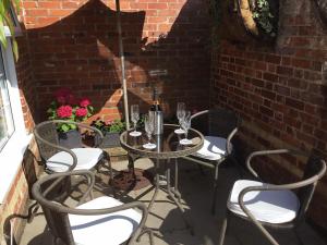 ein Tisch mit Stühlen und Weingläsern auf einer Terrasse in der Unterkunft Coach House Wroxham Holiday Cottage in Wroxham + 4 Fotos