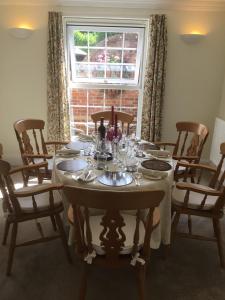 ein Esszimmer mit Tisch und Stühlen und einem Fenster in der Unterkunft Coach House Wroxham Holiday Cottage in Wroxham