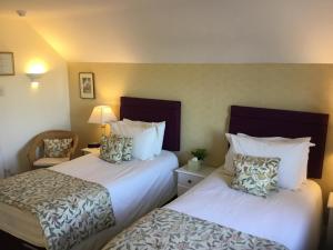 ein Hotelzimmer mit zwei Betten und einem Stuhl in der Unterkunft Coach House Wroxham Holiday Cottage in Wroxham