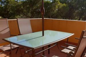 un tavolo in vetro e sedie su un patio di Islantilla Urbasur 1 dormitorio y terraza a Islantilla Altre 8 foto