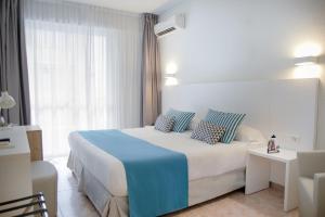 a bedroom with a large white bed with blue sheets at BLUESEA Piscis - Adults Only in Port d'Alcudia