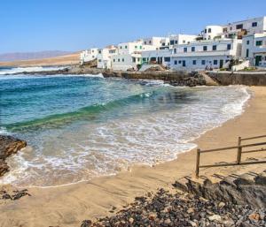 Una playa con edificios blancos y el océano. en Casa Ole, en Caleta de Caballo