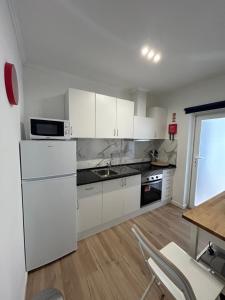 a kitchen with white cabinets and a table and chairs at Casinha da Portela in Sintra