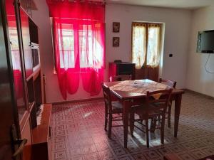 a dining room with a table and red curtains at Villa S'Oliariu in Martis