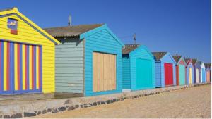 a row of colorful beach huts on the beach at Coastal Comforts in Aspendale