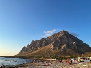 un groupe de personnes sur une plage avec une montagne dans l'établissement Azzurra, à Custonaci