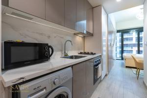 una cocina con fregadero y microondas en Savis Homes - Azizi Riviera 43 - Chic Studio Near Downtown and Business Bay, en Dubái