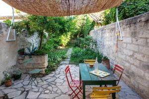 a patio with a table and chairs in a garden at La Maison de Famille in Aigues-Mortes