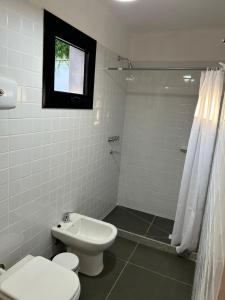 a white bathroom with a toilet and a sink at Casa de la Flor by Posada de la Flor in Colonia del Sacramento