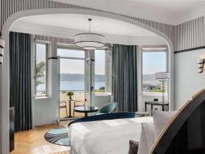 a hotel room with a bed and large windows at The 1932 Hotel & Spa Cap d'Antibes - MGallery Collection in Juan-les-Pins
