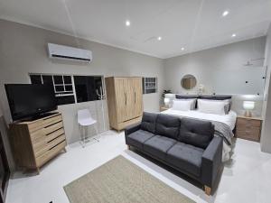 a bedroom with a bed and a couch at Levinia Cottage in Pretoria