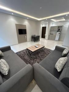 ターイフにあるشقق الاكواخ السبعة للشقق المخدومةのソファとテーブルのあるリビングルーム