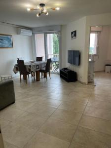 a living room with a table and chairs and a television at Grabels Soleil Calme & Piscine in Grabels